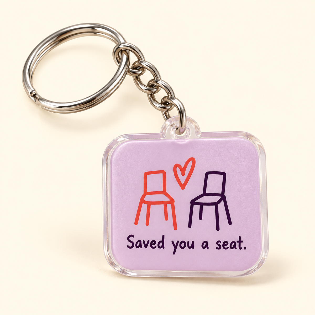 Lavender keychain with coral and plum chairs, a coral heart, Saved you a seat lettering, and silver-tone hardware