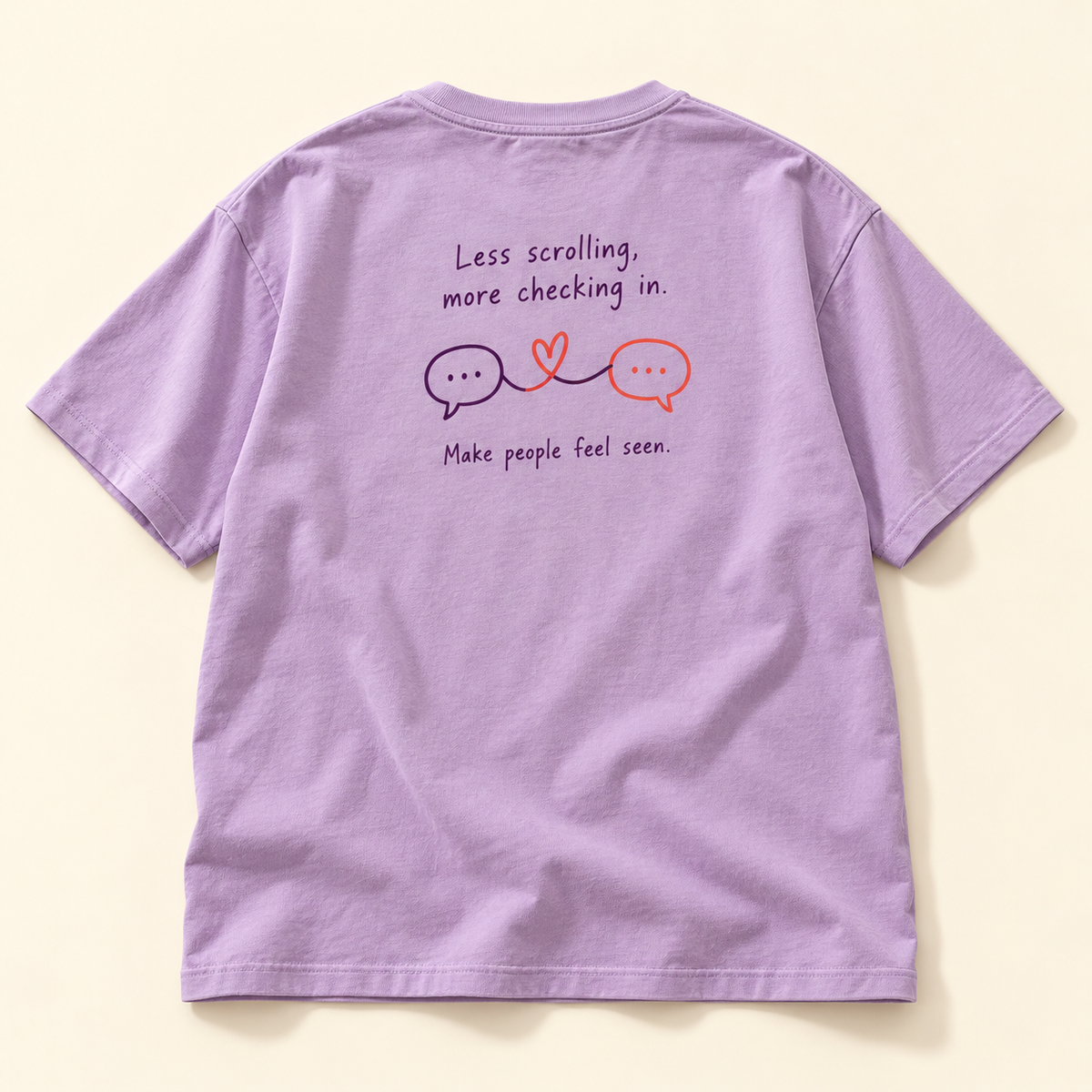 Lavender tee shown from the back with Less scrolling, more checking in lettering, heart-linked speech bubbles, and Make people feel seen beneath